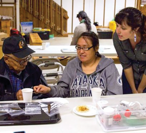 Village elder George Pleasant, Yup’ik speaker and translator Mary Church, and Anna Sloan looking at artifacts in the midst of interview research. 