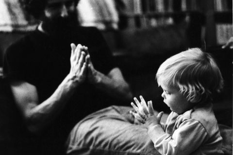 Scott Coltrane as a young father, teaching son Colin “patty cake.”