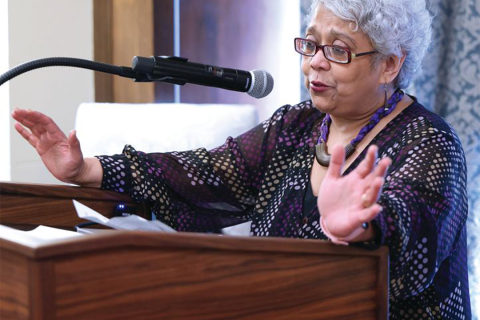 Sangita Gopal speaking at a podium.