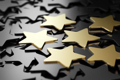 Six gold stars rest on a pile of other stars.