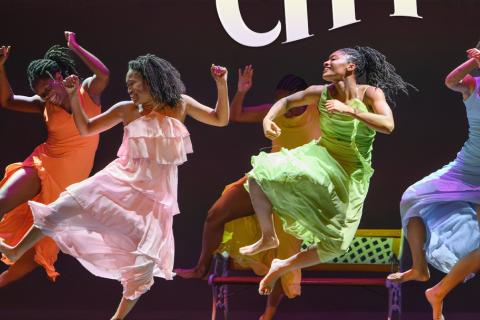 Four women dancing in colorful dresses.