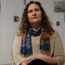 Sarah Grew sitting among hanging photos of trees printed on glass.