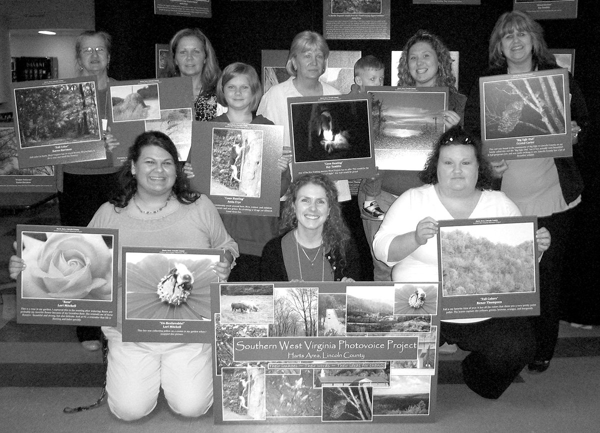 Shannon Elizabeth Bell, front center, with Harts Photovoice Group at their 2009 exhibit in West Virginia. Bell served as a bridge to help women she studied bring forward their stories about devastation to their community by the coal industry.
