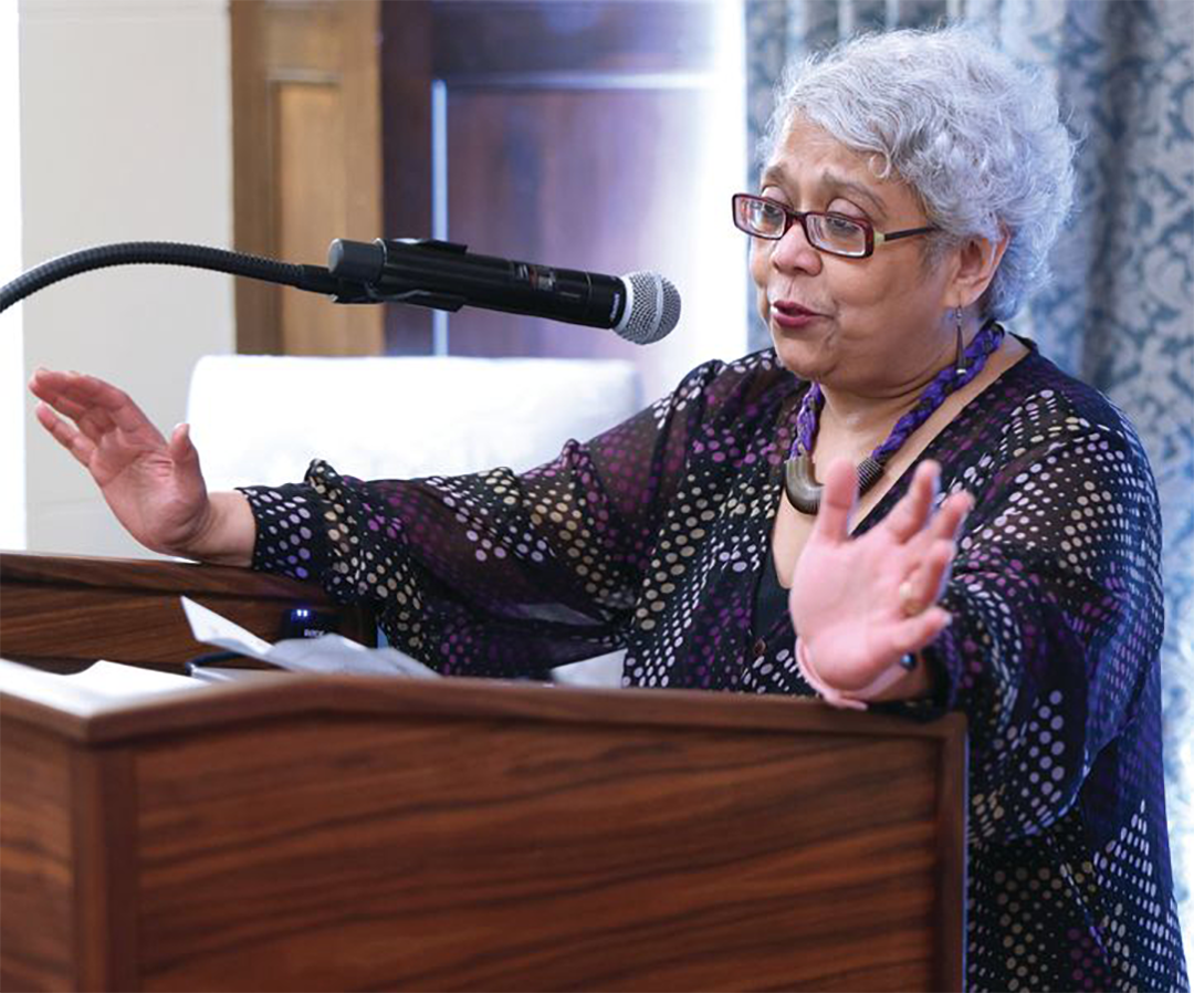 Sangita Gopal speaking at a podium.
