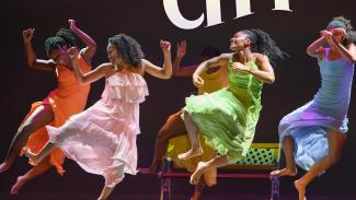 Four women dancing in colorful dresses.
